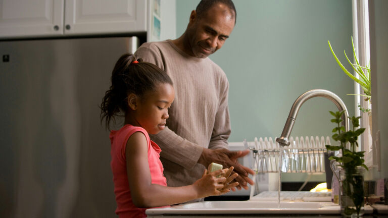 man and child washing hands in a sink