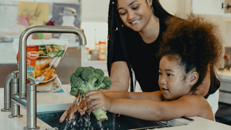 woman and child washing vegetables in the sink
