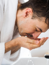 man washing his face in a sink man washing his face in a sink