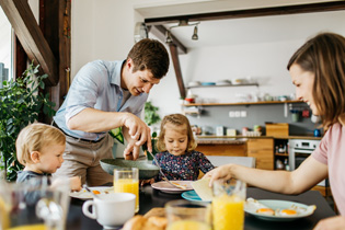 A young family of four having breakfast together at a table.
