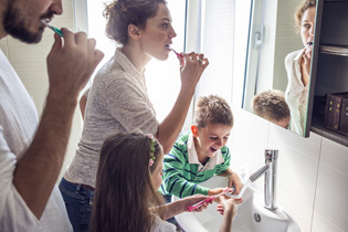 A family of four all brushing their teeth together.
