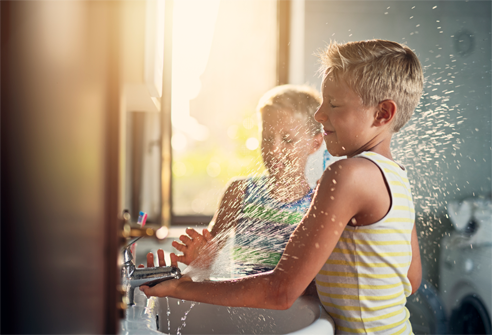 Two boys playing with spraying water.