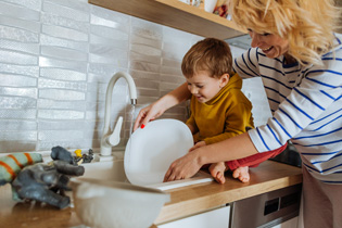 A mother and child washing a dish.