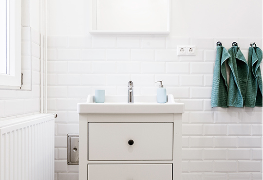 Simple white bathroom sink with subway tiles and radiator.
